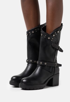 Czarne skórzane botki na masywnym obcasie, ozdobione srebrnymi ćwiekami i paskami, z zagiętym wykończeniem wierzchu i teksturowaną powierzchnią.