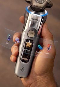 Philips i9000 Prestige Ultra scheerapparaat, metallic zilver, ergonomisch ontwerp, met aanpasbare scheeropties, knoppen en een verlichte interface.