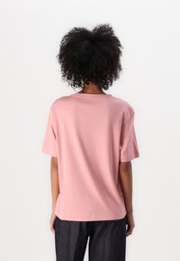 Šviesiai rožinė trumpa rankovė t-shirt, pagaminta iš minkštos medvilnės. Laisvas kirpimas su apvaliu iškirpimu. Lygi tekstūra ir paprastas dizainas, be matomų raštų.