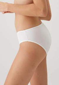 Witte katoenen hoge taille slip met een soepele textuur, elastische tailleband en naadloos ontwerp, gezien van opzij.