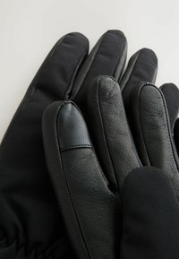 Guanti neri realizzati con una combinazione di pelle e un materiale morbido ed elastico. Il design presenta dita con sezioni distinte e texture lisce.