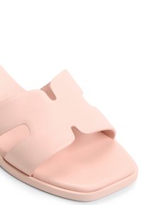 Sandale glissante rose en cuir texturé avec une large sangle ornée d'accents découpés, bout carré et finition lisse.