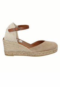 Sandalo con zeppa in suede beige, dotato di cinturino alla caviglia intrecciato e suola in juta. Presenta una punta arrotondata e un cinturino regolabile marrone.