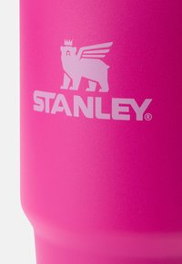 Ružový nerezový pohár s matným povrchom. Zobrazuje biele logo medveďa s krídlami nad textom "STANLEY."