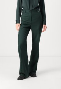 Green tailored trousers with a straight-fit design, high waist, two front pockets, and a button closure. Smooth fabric and subtle seam details.