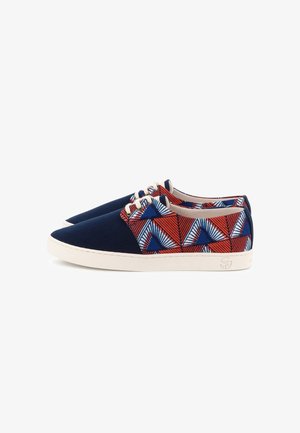 Paire de baskets basses avec bouts bleu marine, semelles blanches et tissu à motifs géométriques rouge, bleu et blanc sur les côtés, avec lacets blancs.