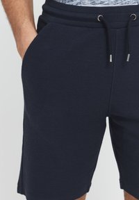 Mørkeblå bomuldsshorts med elastisk talje, snøretilslutning og sidelommer. Blød tekstur med ribbet stof.