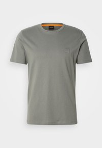 T-shirt gris uni à manches courtes et col rond, avec une petite étiquette logo "BOSS" sur le côté gauche de la poitrine et un détail orange à l'intérieur du col.