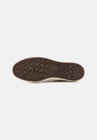 Semelle de chaussure de sport en caoutchouc marron avec un motif texturé de losanges et de lignes, bordée d'un bord blanc, design plat et durable.