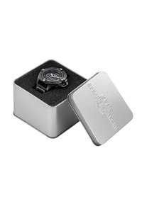 Reloj de pulsera negro con múltiples esferas y una correa negra texturizada, presentado en una caja de metal plateada con un interior de espuma.