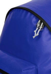 Blå nylonryggsäck med rundad topp, svarta dragkedjeinslag och reflekterande dragsnoddar. Texturerad yta utan framträdande mönster.