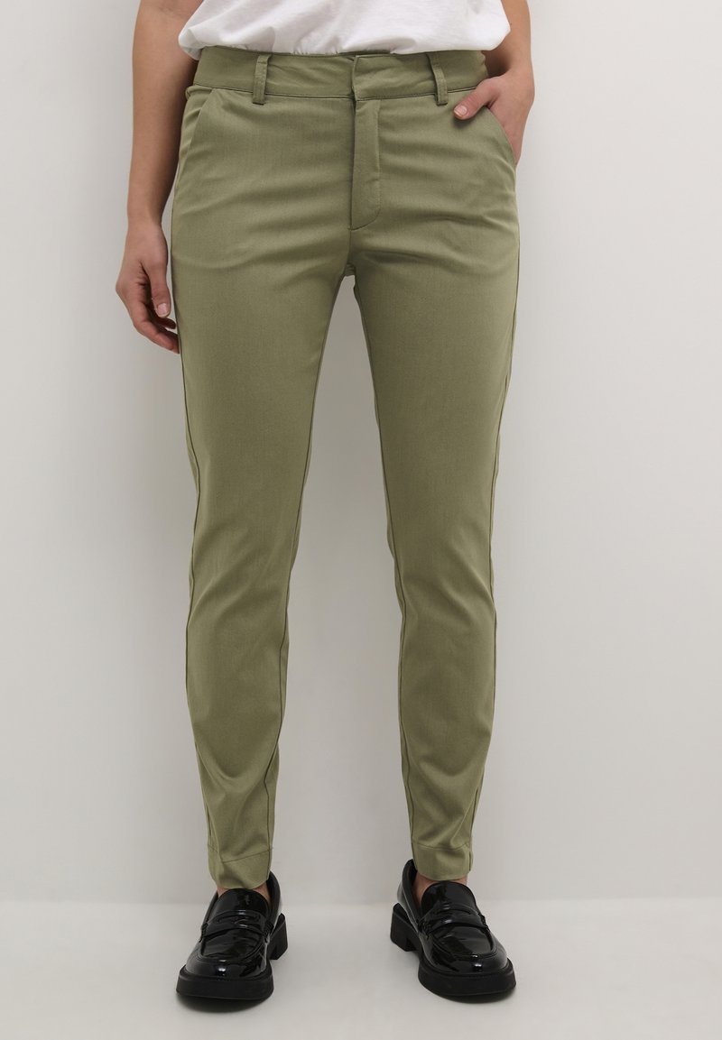 Olive green slim-fit trousers with a smooth texture, front pockets, and a classic waistband, paired with black glossy shoes.