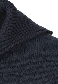 Close-up van de kraag van een donkerblauwe geribbelde gebreide trui met een kleine zichtbare rits langs de rand.