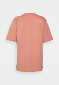 Camiseta de manga corta color coral claro con un pequeño logo claro "The North Face" en la parte superior derecha de la espalda, diseño liso, en posición plana sobre un fondo blanco.