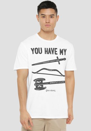 Young man wearing a white t-shirt with "YOU HAVE MY" text and illustrations of a sword, bow, and axe from Lord of the Rings.