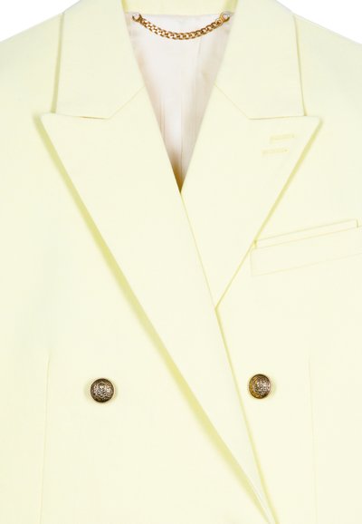 Dubbelbreasted blazer van lichtgele stof, met gouden hardware knopen, notch-lapels en een zak aan de linkerkant. Gestructureerde afwerking.