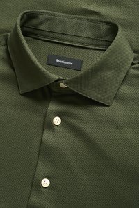 Olijfgroene overhemd met knopen gemaakt van gestructureerde stof met een subtiel patroon, voorzien van een klassieke kraag en witte plastic knopen.