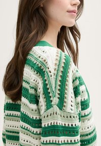 Jersey de punto con rayas horizontales verdes y blancas, con detalles de calados y un escote en forma de V. Ligero, con un acabado texturizado.