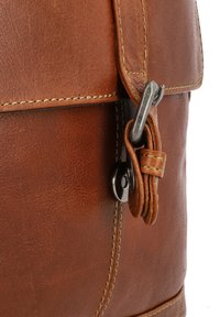Bruine leren schoudertas met een gestructureerde afwerking, voorzien van een metalen sluiting en gestikte accenten voor extra duurzaamheid.