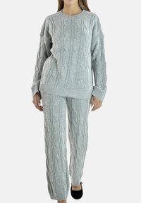 Ensemble pull et pantalon en tricot gris avec motif torsadé, poignets côtelés et coupe décontractée. Le tissu semble doux et texturé.