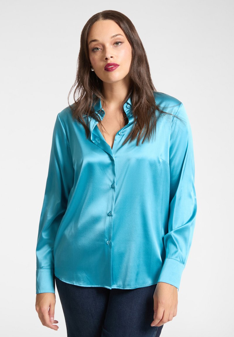 Turkusowa satynowa koszula z zapięciem na guziki z przodu, długimi rękawami i zaokrąglonym dołem. Gładka faktura z połyskującym wykończeniem. Widoczne detale guzików.