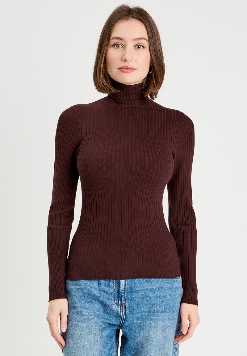 Bordeauxfarvet ribbet turtleneck sweater med lange ærmer og en tætsiddende silhuet, parret med lyseblå højtaljede jeans.