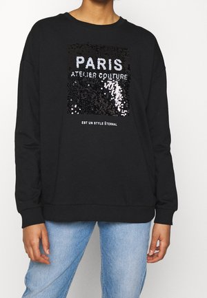 Felpa nera con una grafica in paillettes che recita "PARIS ATELIER COUTURE" in argento e bianco, con polsini e orlo a coste.