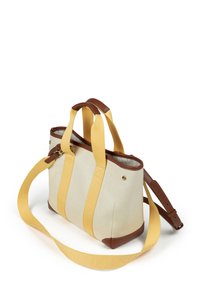 Sac en toile crème avec des poignées jaunes et des accents en cuir marron. Dispose de doubles poignées et d'une bandoulière ajustable pour plus de polyvalence.