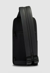 Sac à dos noir avec un corps en tissu texturé et des accents en cuir lisse. Comprend une poche zippée et une sangle réglable rembourrée.