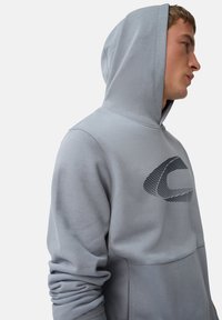 Hellgraues Hoodie mit einem großen schwarzen Grafiklogo auf der Brust. Verfügt über eine Kordelzugkapuze und gerippte Ärmelbündchen für eine enge Passform.