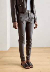 Op maat gemaakte grijze broek met een gladde textuur, voorzien van twee voorste knopen en een slim fit. Gecombineerd met zwarte, open teen blokhak sandalen.