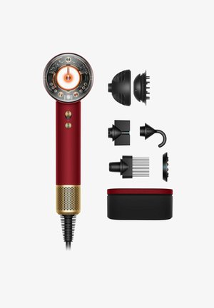 Roter Haartrockner mit runder Düse, ausgestattet mit einem Licht und Reglern, goldenen Akzenten sowie mehreren abnehmbaren schwarzen Aufsätzen, die daneben angeordnet sind.