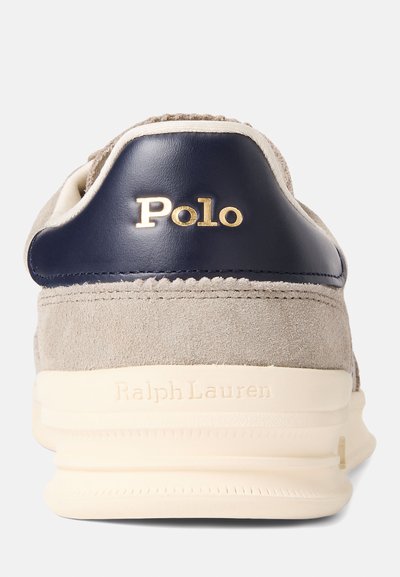 Szürke velúr sportcipő tengerészkék bőr részletekkel. Arany "Polo" logó a sarkon és "Ralph Lauren" debossed a talpon. Simább textúra, párnázott talp.