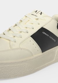 Κρεμ sneaker Armani Exchange με μαύρο πλαϊνό πάνελ, λευκά κορδόνια, υφασμένο πέλμα και λογότυπο A/X στη γλώσσα και στην πλευρά.