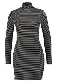 Musta-valkoinen raidallinen pitkähiha dressi korkealla kauluksella. Säännelty muoto, jossa on sileä tekstuuri ja vaakasuorat raidat koko matkalla.