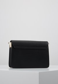 Borsa a tracolla in finta pelle nera con chiusura a patta. Presenta dettagli in metallo dorato, una texture liscia e una forma rettangolare.