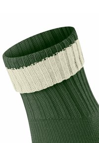 Zielona wełniana skarpetka z szerokim beżowym ściągaczem. Teksturowany materiał z pionowymi liniami, z gładkim przejściem od ściągacza do reszty skarpetki.