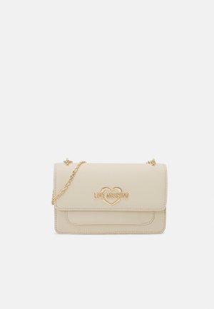 Sac à bandoulière beige Love Moschino avec bandoulière en chaîne dorée et logo cœur doré sur le rabat avant sur fond uni.