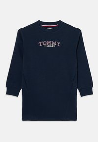 Tmavomodré šaty so sveterom s kvetinovou výšivkou "TOMMY HILFIGER." Majú okrúhly výstrih, dlhé rukávy a bočné vrecká.