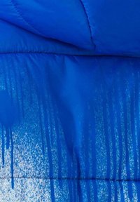 Giubbotto imbottito blu con finitura lucida, caratterizzato da un effetto sfumato con gocce bianche e una texture trapuntata. Progettato per il freddo.