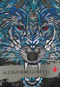 Sort stof med et blåt og gråt broderet løvedesign med røde øjne, suppleret af et gråt bånd med teksten "ALessandro Zavetti."