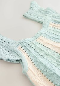 Helles blaues gehäkeltes Oberteil mit kurzen Ärmeln, das abwechselnd gestreifte Pastellrosa-Design aufweist. Strukturiertes Muster mit offenen Webdetails.