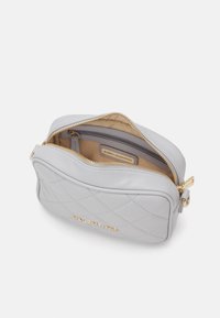 Szürke steppelt kézitáska arany színű részletekkel, elől arany logóval és belső zsebbel. Cipzáras záródás, puha bőrből készült.