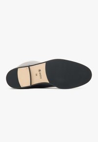 Czarna podeszwa buta z fakturowaną gumową powierzchnią, jasnokolorowym blokowym obcasem i markowym akcentem. Posiada gładkie krawędzie i wzmocnione szwy.