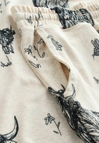 Beige stof med sorte dyre- og blomstermotiver, med elastisk talje og detalje med lomme. Blødt, tekstureret materiale.