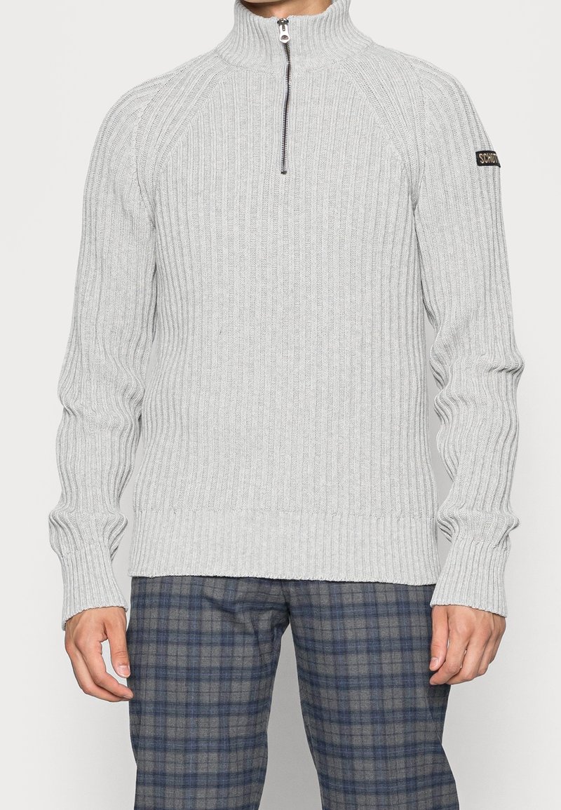 Pull gris clair côtelé avec un col montant et une fermeture à moitié éclair. Comprend des manches longues et une taille ajustée. Petite étiquette logo sur la manche.