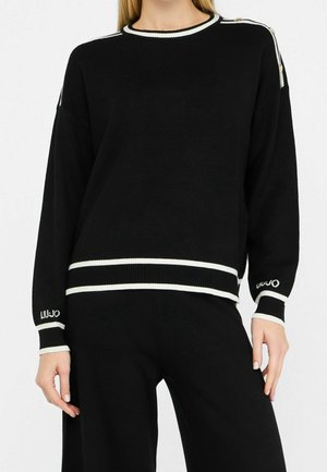 Maglione nero a maniche lunghe con rifiniture bianche su polsini, scollo e orlo, caratterizzato da bottoni dorati sulle spalle e ricamo di testo sulle maniche.