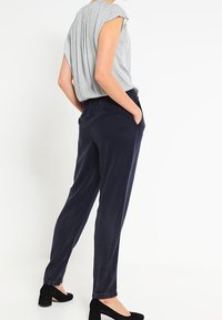 Šedá blůza s vzorem a krátkými rukávy je zkombinována s námořnickými kalhotami s úzkým střihem. Celý outfit doplňují černé uzavřené lodičky.