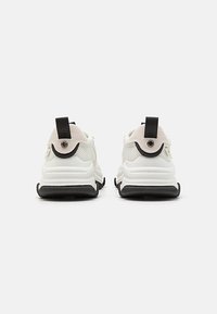 White sneakers featuring a mesh upper, black rubber sole, and a rounded design. Back has textured accents and fabric pull tabs.