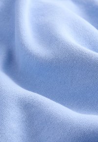 Tissu tricoté bleu clair doux avec une texture fine et des plis subtils.